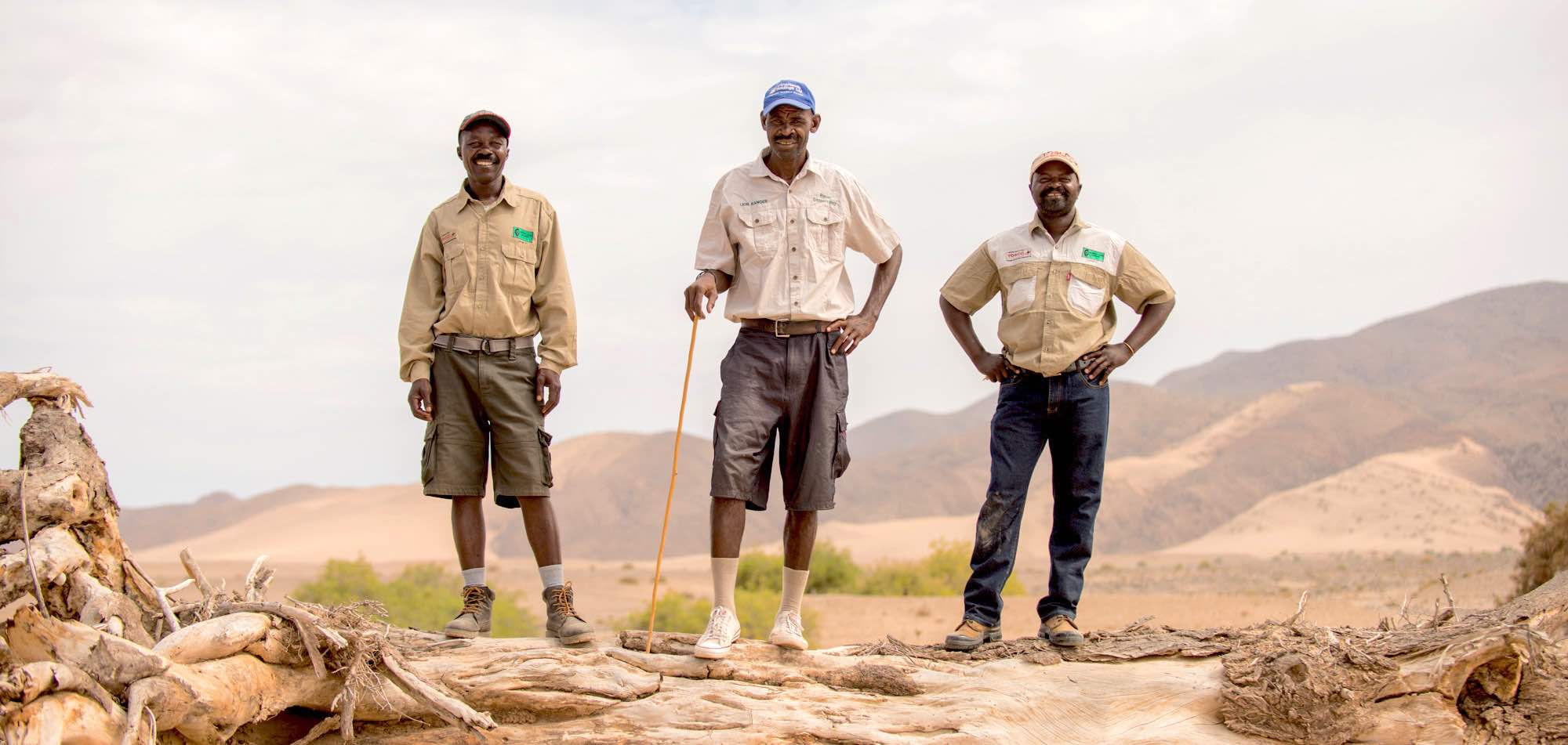 Three Namibian game guards smile at the camera.