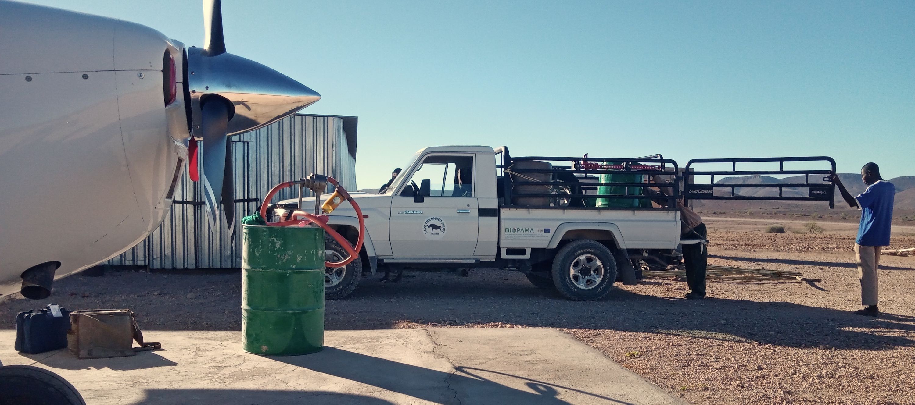 The plane, and several fuel drums being delivered by landcruiser.