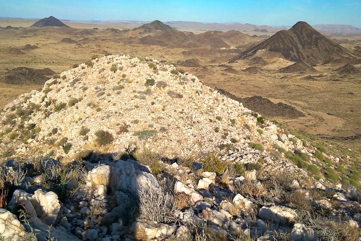 A view looking down and across a valley, with mountains in the background.