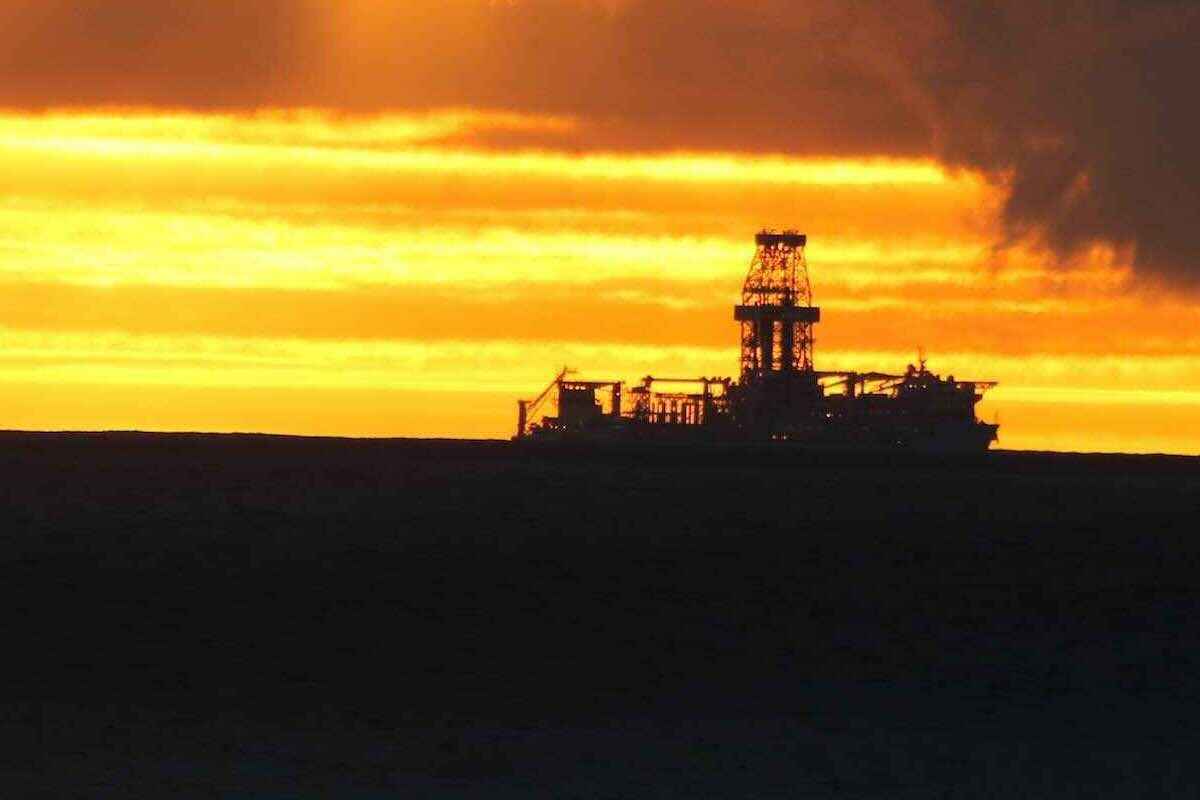 A desert scene with tufts of grass and the tops of bushes poking through hillocks of sand.