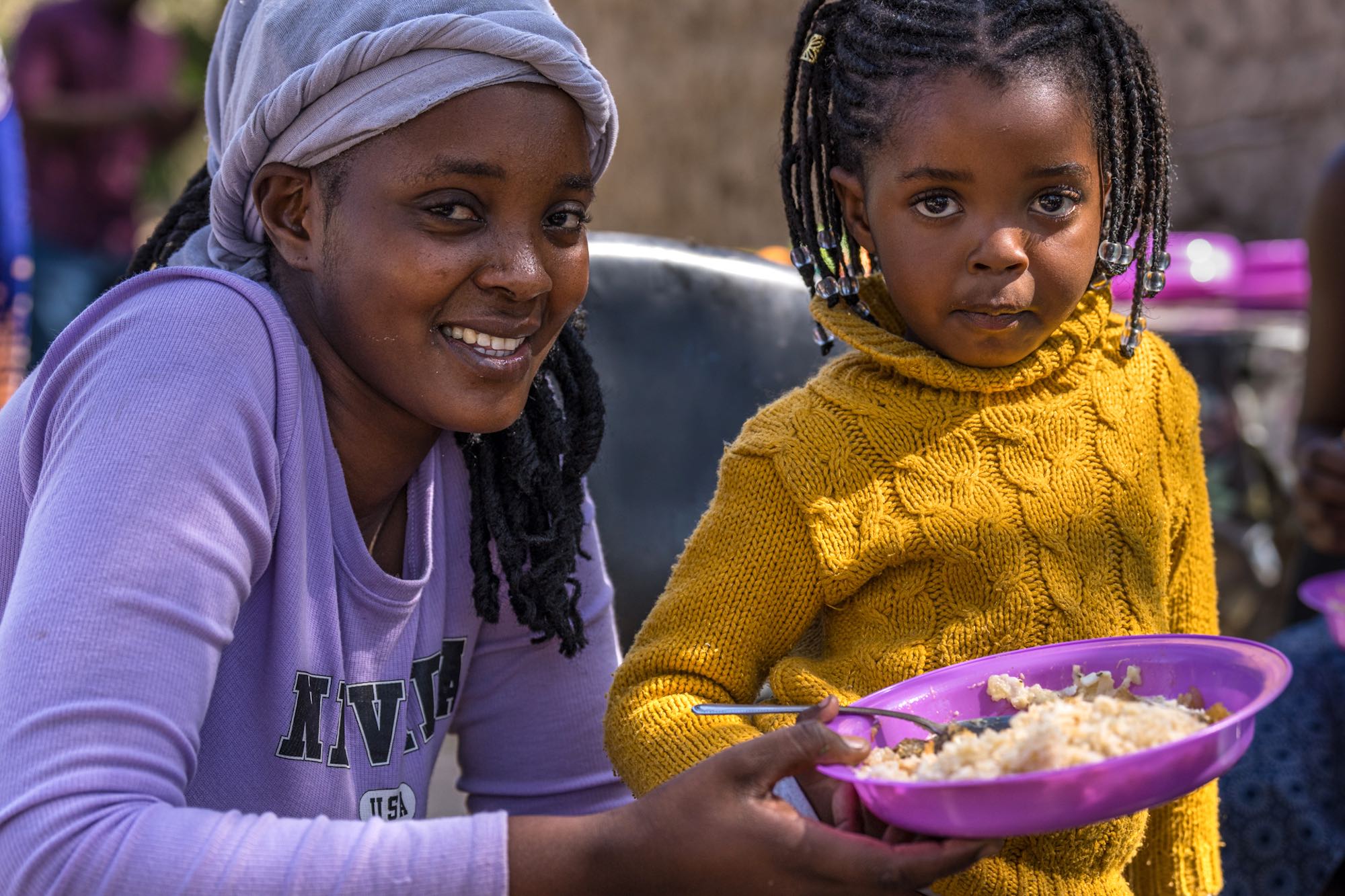 A woman and her young daughter smling at the camera.