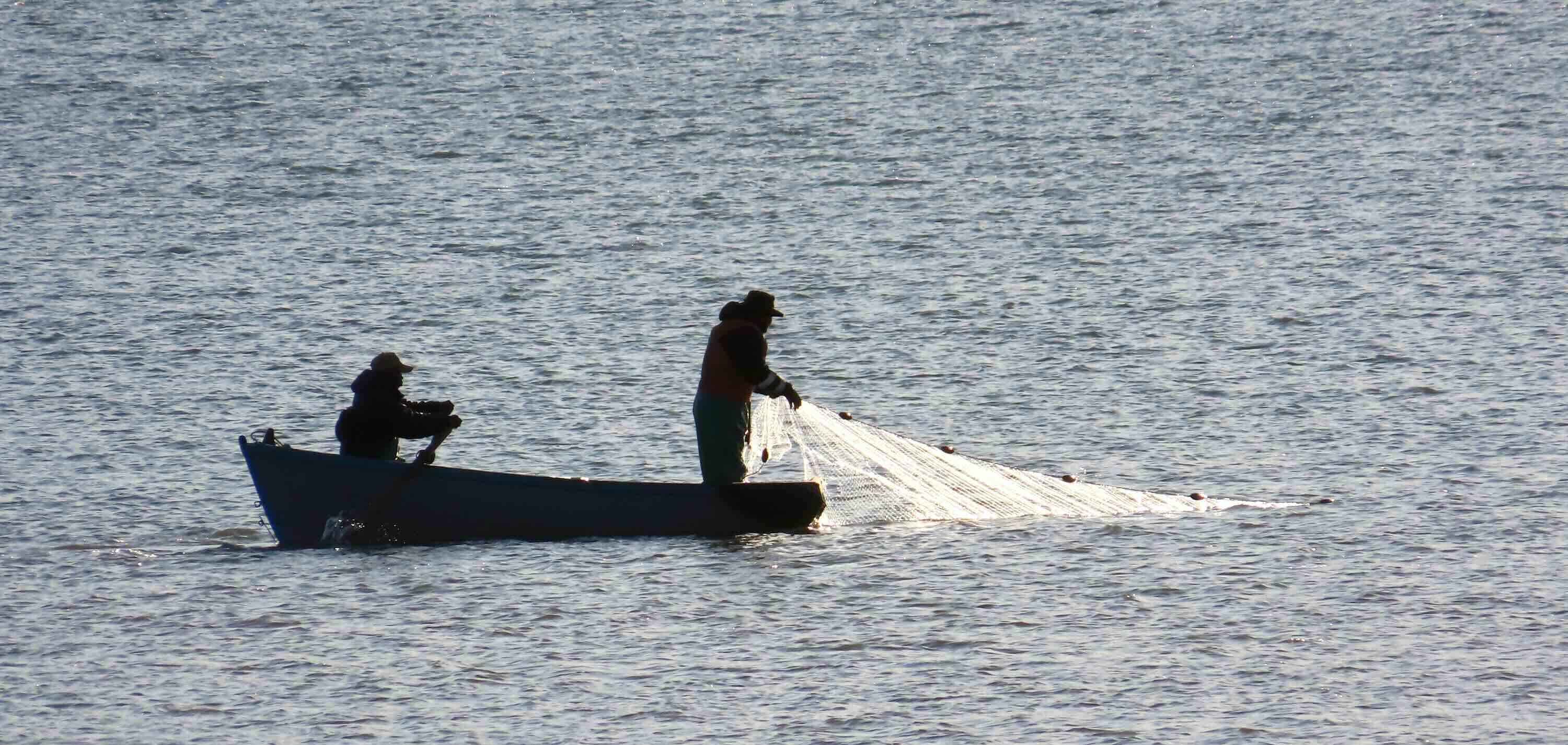 Two fishermen in a small boat.