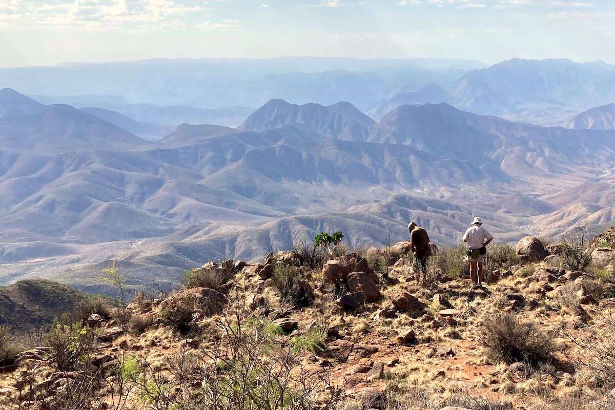 Two men gazing across a vast mountain landscape.