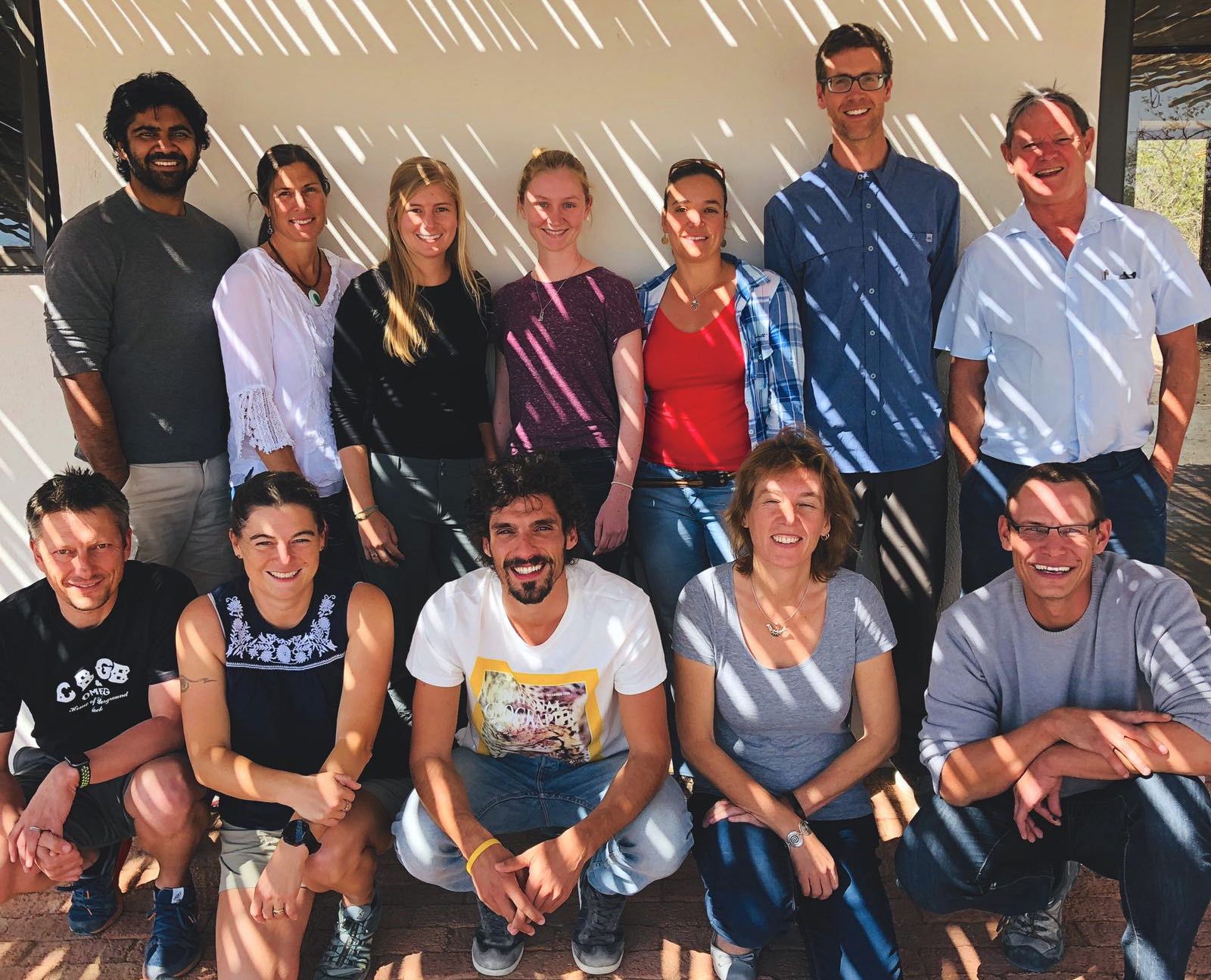 Workshop participants smile at the camera. Seven stand in the back row, and five sit in front.