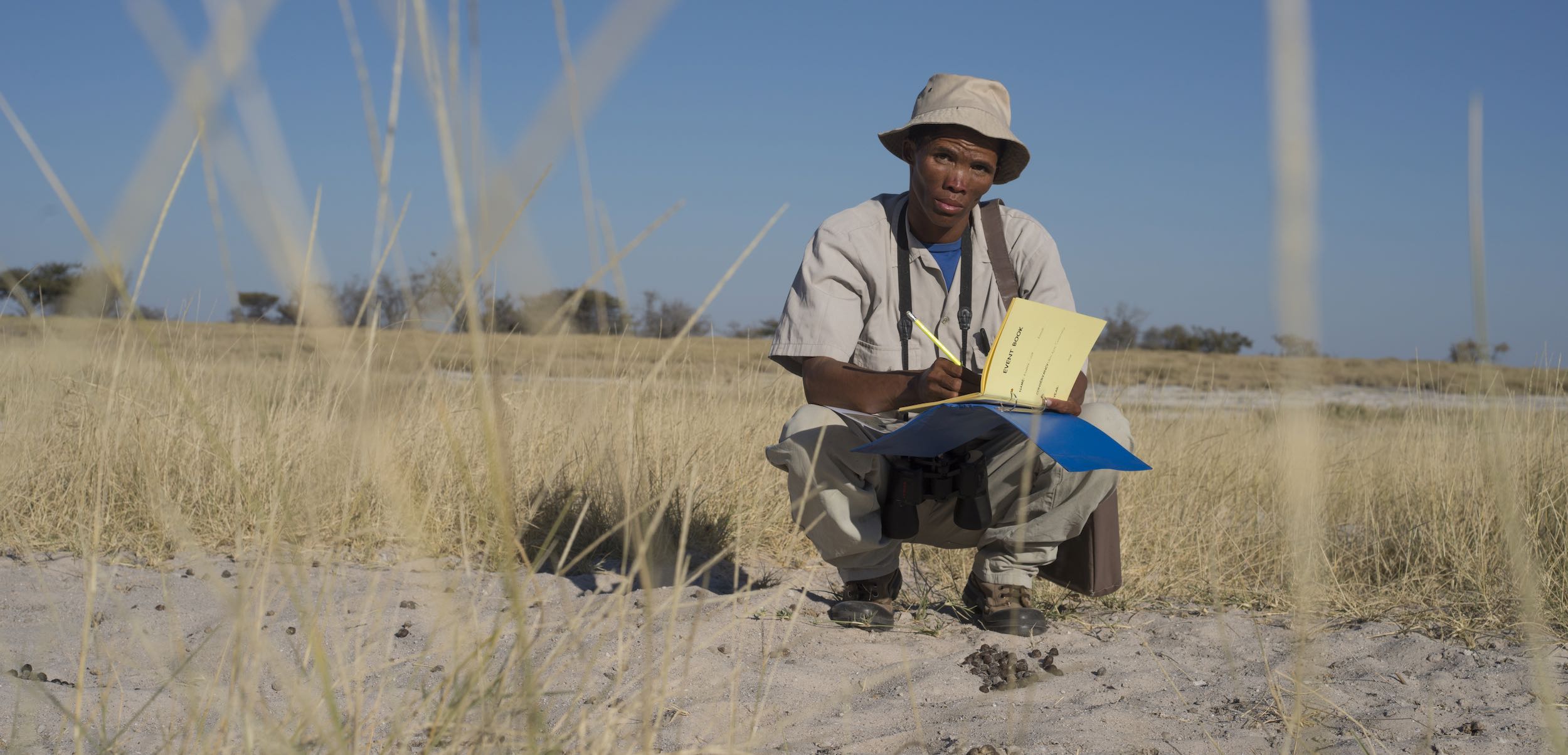 A game guard crouches down while entering information into his Event Book.