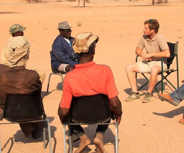 A group of people sitting on a circle of chairs in the desert - a meeting with a view!