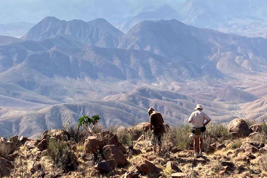 Two men gazing across a vast mountain landscape.